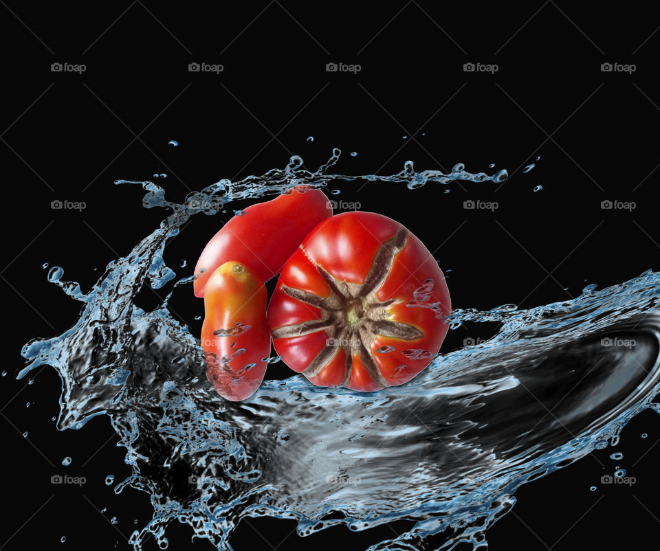 Red tomatoes in splashes of water on a Black background