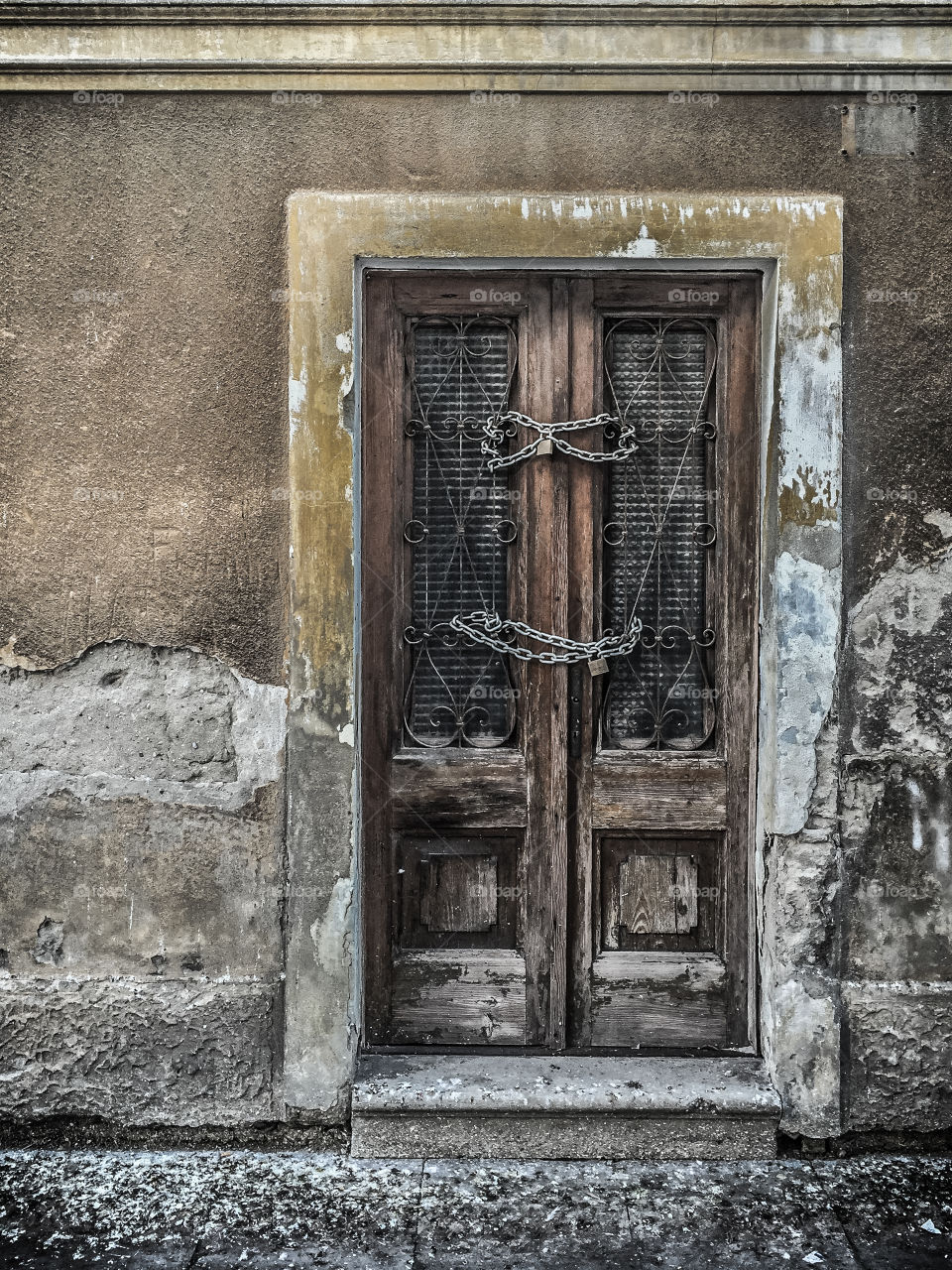 Wooden gate locked with a chain with weathered wall