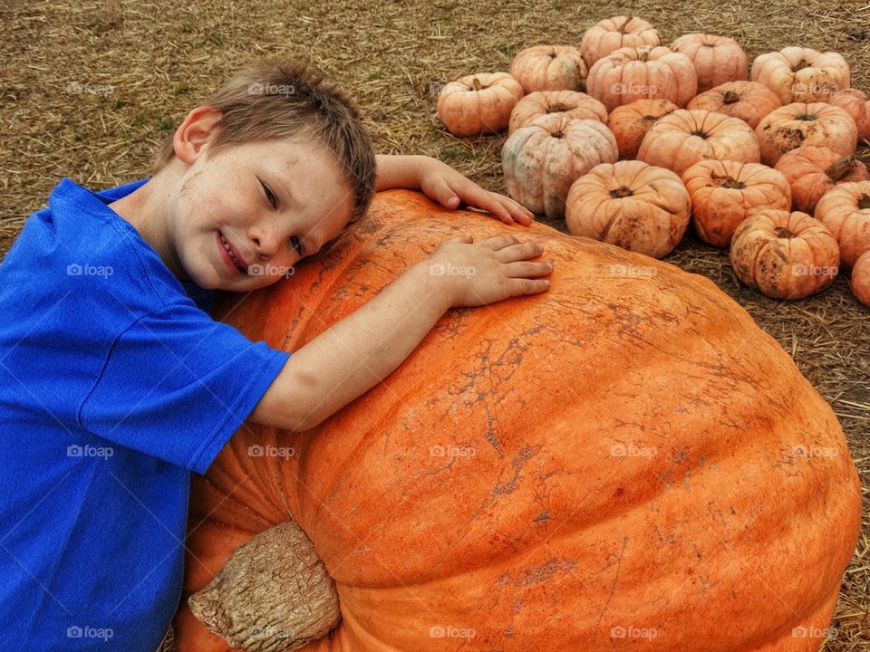 Young Boy Hugging A Giant Pumpkin
