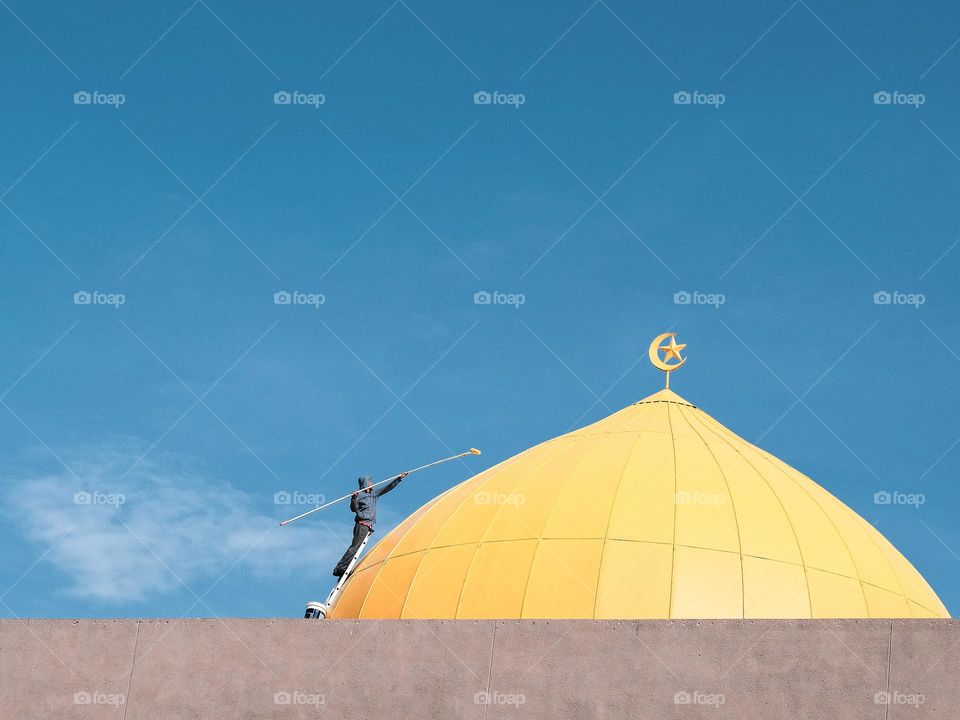 A new coat of yellow paint on the mosque dome against blue sky