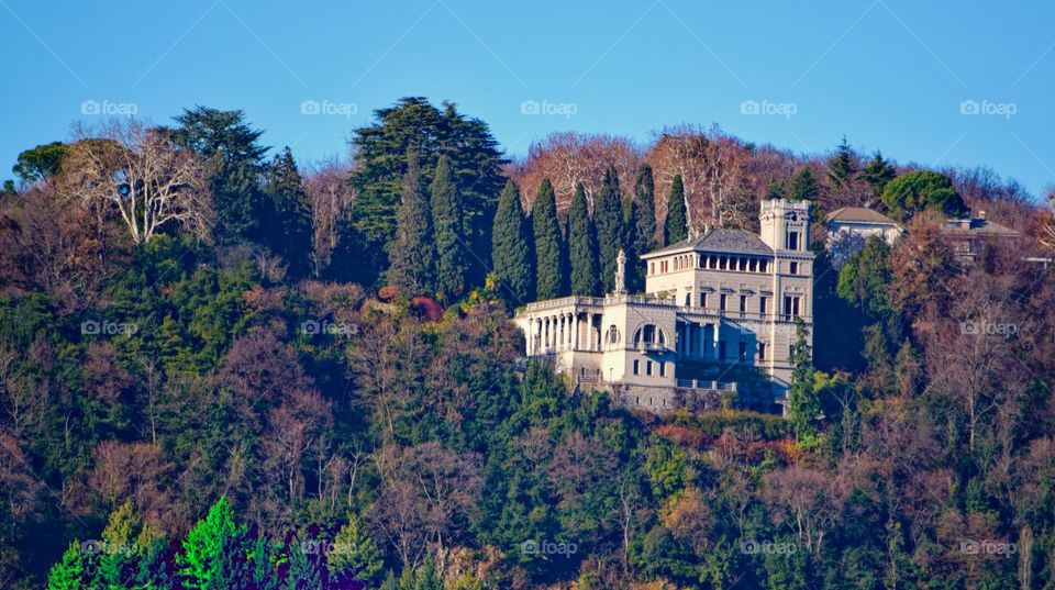 Chateau on side of hill surrounded by trees in autumn