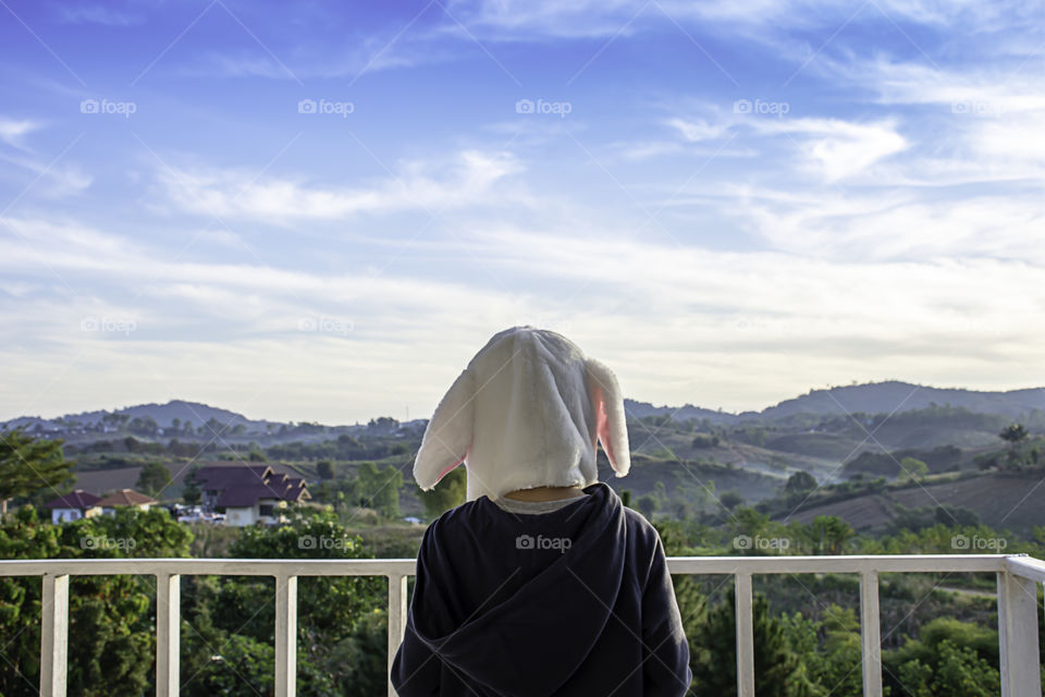 Children wearing winter coat and hat On the balcony overlooking the mountains and the sky.