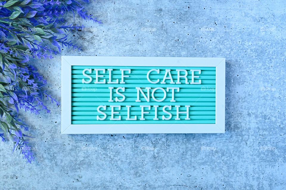 Self-care is not selfish, words on pale background lavender top view