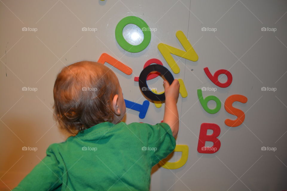Boy playing with magnetic numbers and letters on a magnetos board
