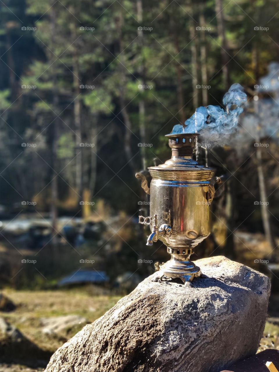 A smoking samovar on a stone in the forest