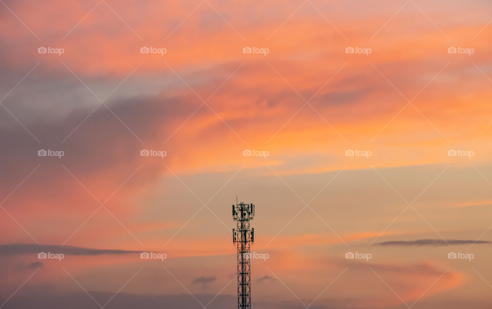 Evening sunset light is orange after the telephone receiver antenna.