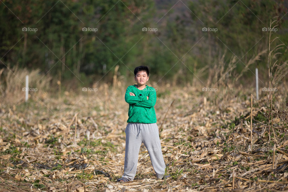 Boy cross one's arm in the farm field 