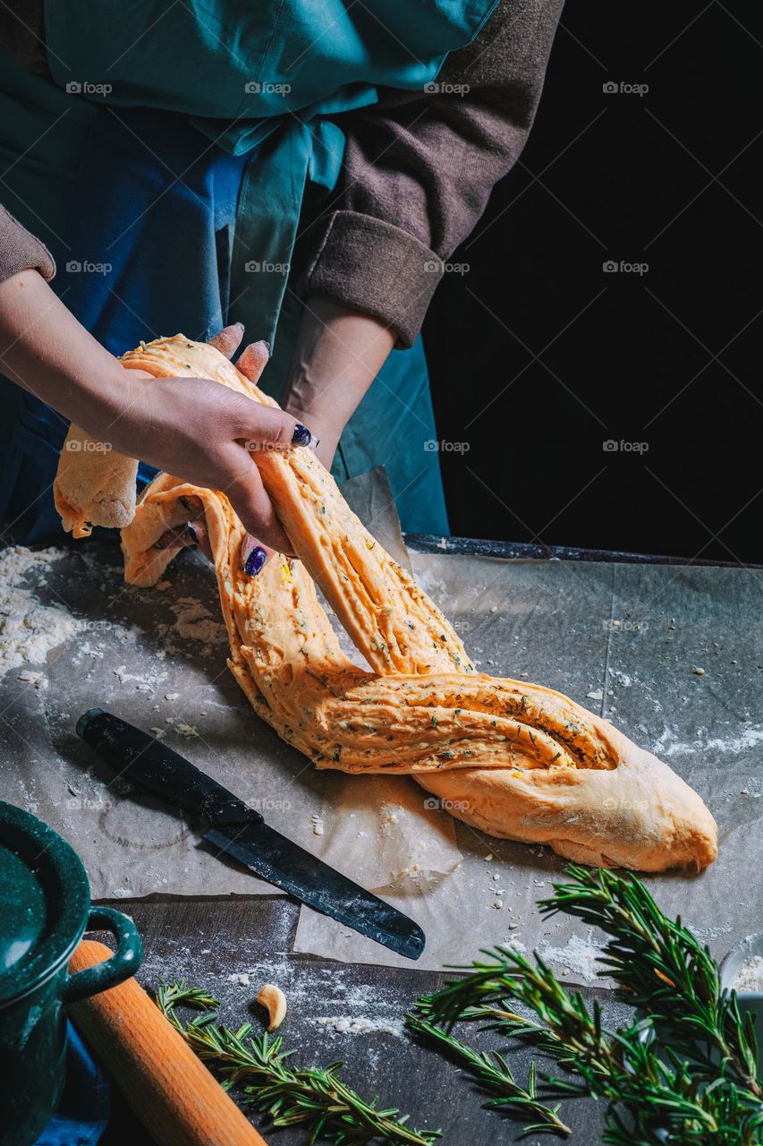 Women's hands, flour and dough. Levitation in a frame of dough and flour. A woman in an apron is preparing dough for home baking. Rustic style photo. Wooden table, wheat ears and flou.Emotional photo