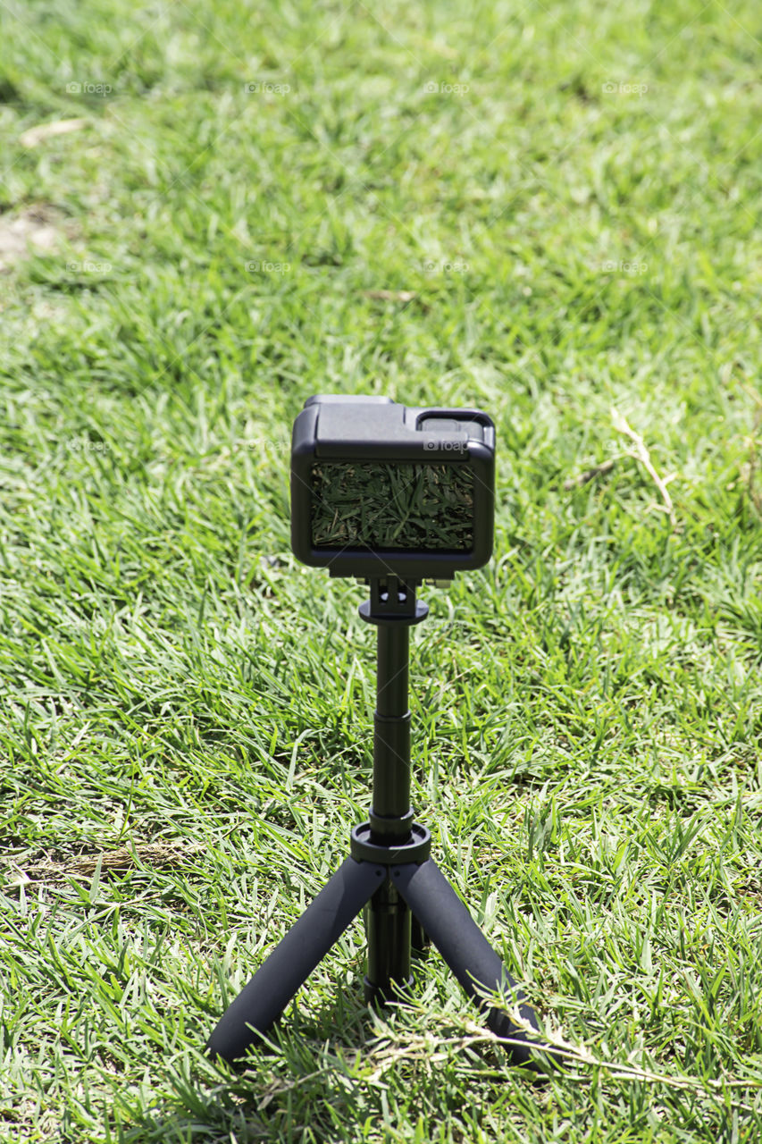 Camera and video with small black stand on On the green grass