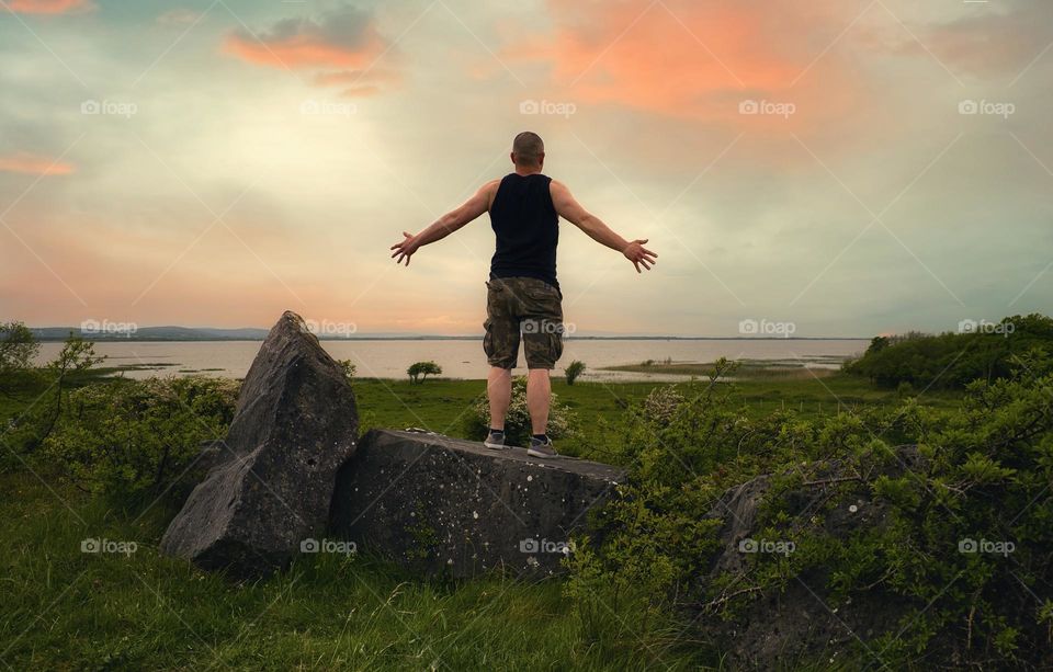 Man standing on the rock on top of the hill and watching sunset with stunning view on Corrib lake ,Galway ,Ireland