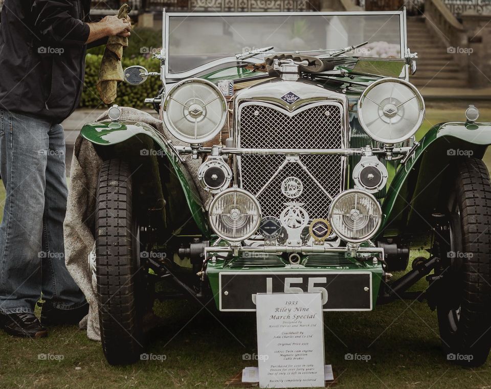 Man performing maintenance on an old vintage, green car