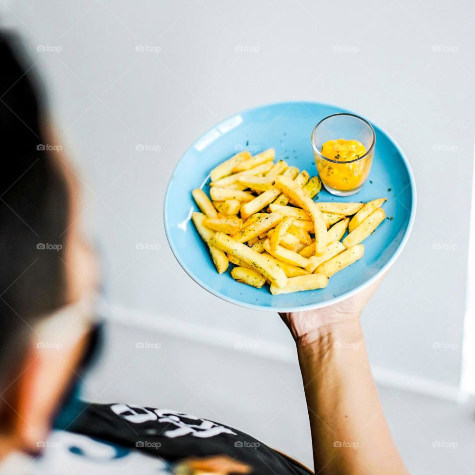 Your order is coming! French fries are served on a plate combined with cheese sauce. Snacks. Food. Eat. Cafe. Delicious. Servant. Delivered. Order. Buy. Pay. Plate. Blue. Crispy. Fritters. Sauce. Cheese.