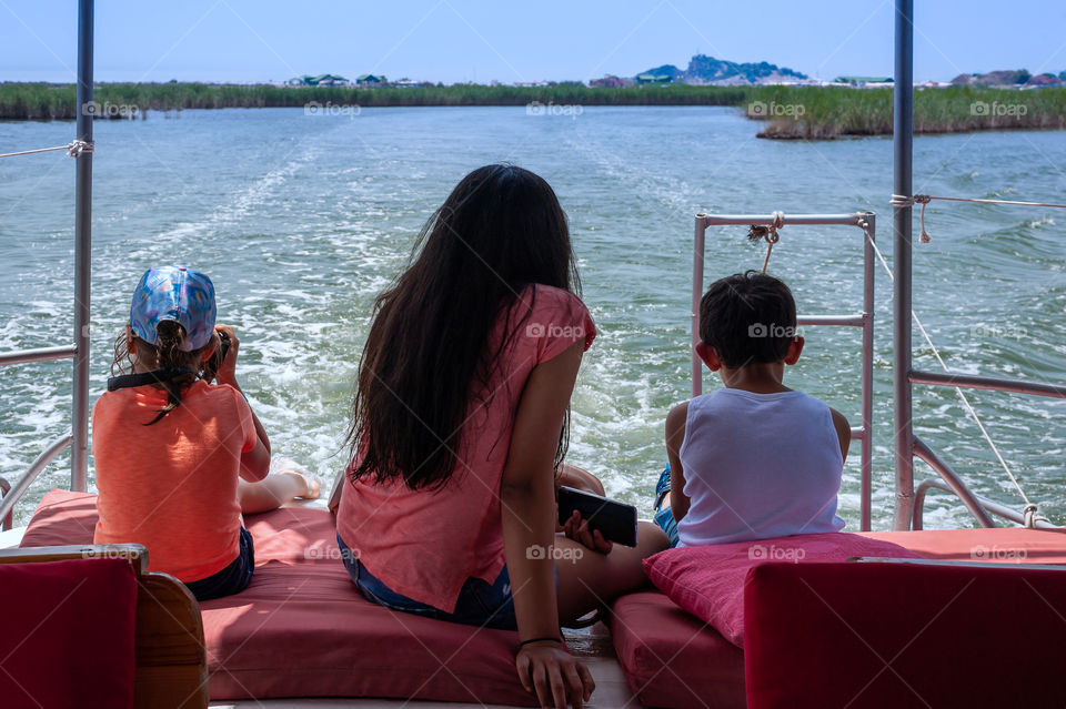 Children on river motor boat watching land dissappear in distance. Already missing holidays.