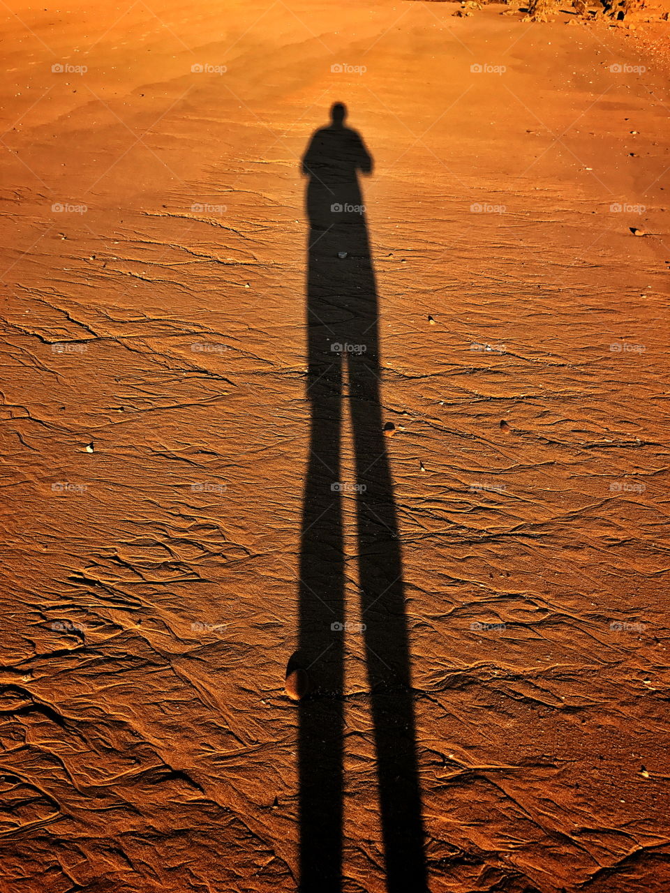 Long human shadow on red dirt