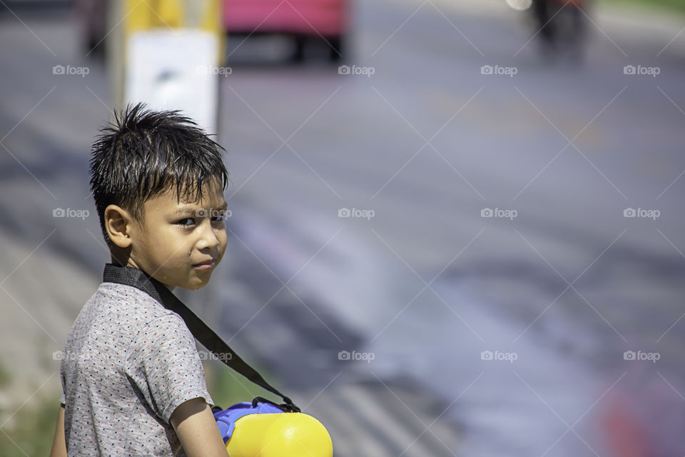 Asian boy holding a water gun play Songkran festival or Thai new year in Thailand.