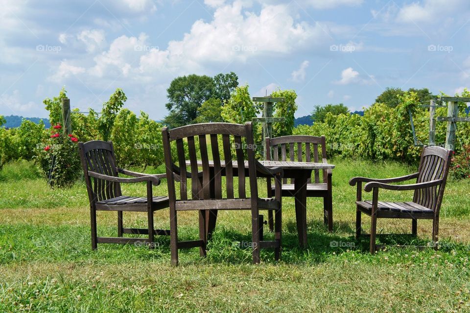 Empty table and chairs on grassy field