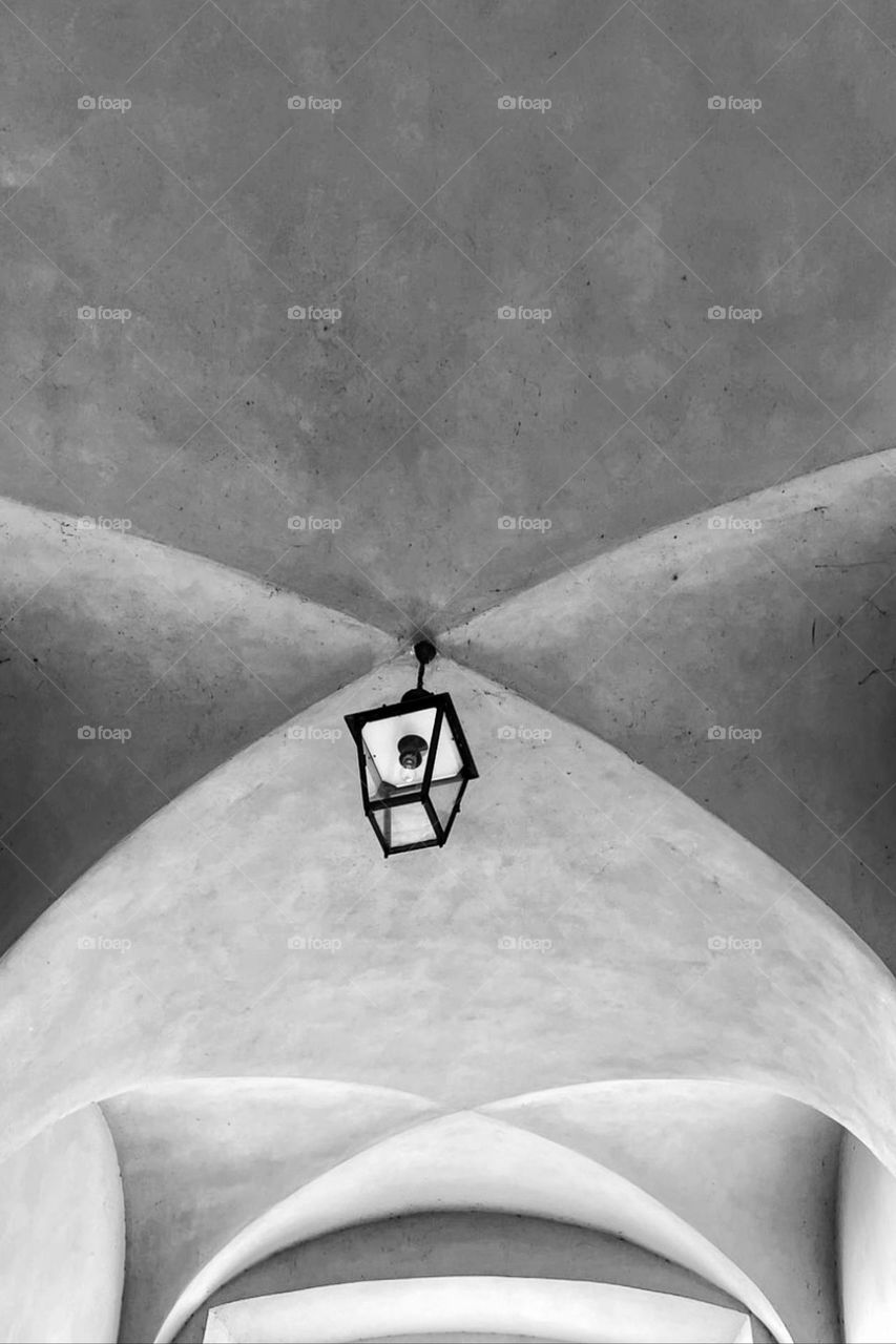 Black and white photo of a cross vault with a hanging ceiling lamp