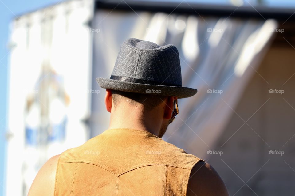 Young man wearing fedora hat outdoors back view