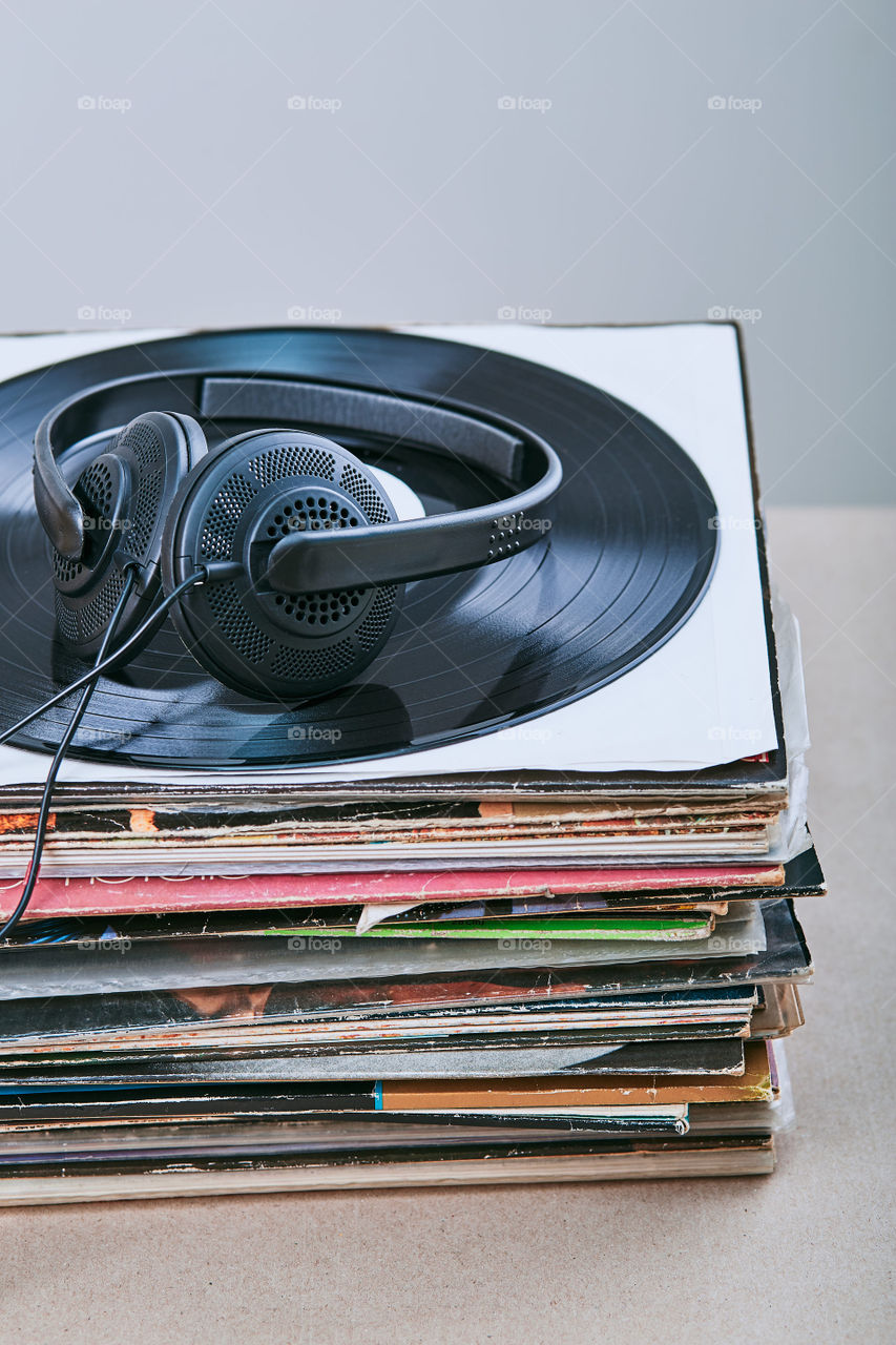 Stack of many black vinyl records, headphones put on the top of vinyls. Copy space for text. Candid people, real moments, authentic situations