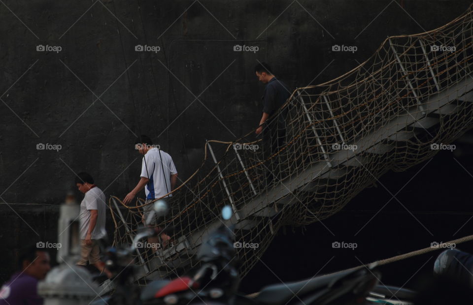 Passenger get off at the one time afternoon. Ship anchored by the caps, and family, person ready pick up to the last destiny of them. Automatic of surround crowd issidental happening there .