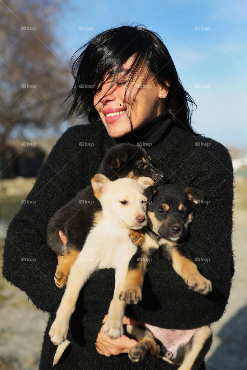 happy, beautiful girl, carries puppies in her hands, stray dogs