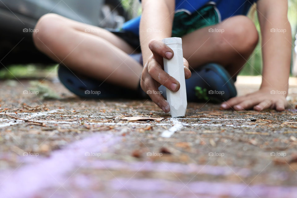 Child drawing with chalk on sidewalk