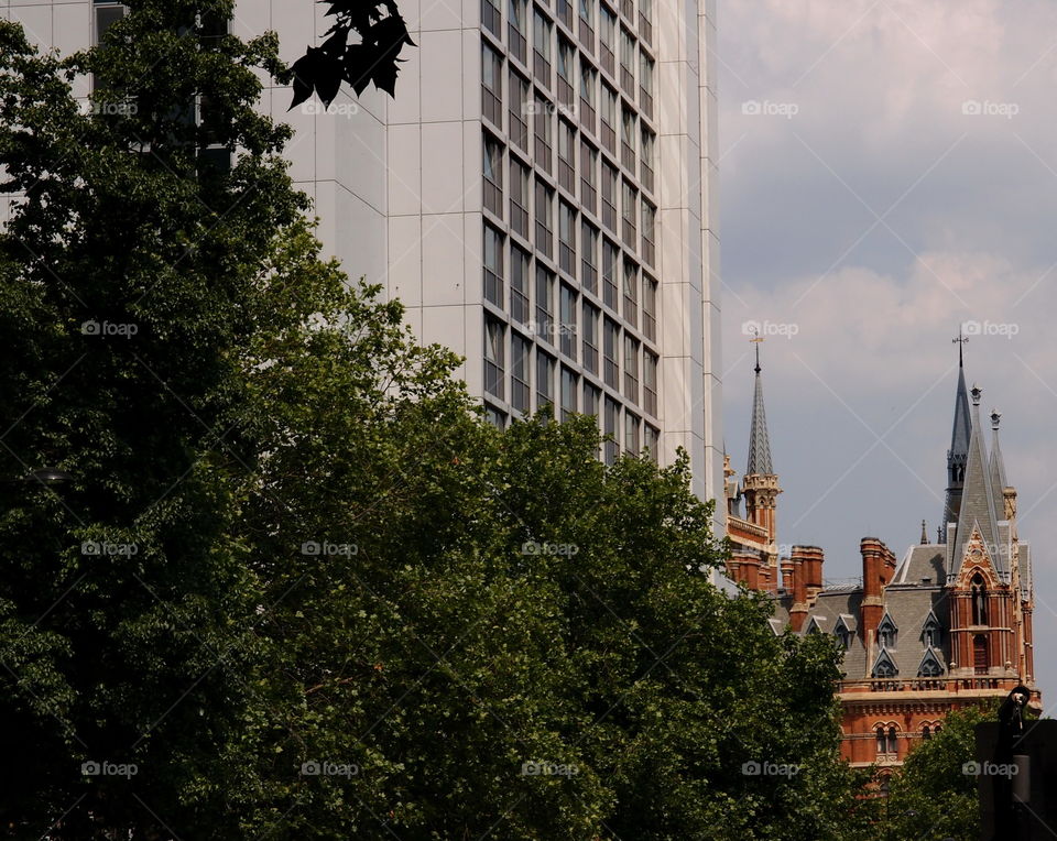 The contrast of modern architecture with older architecture and nice landscaped green trees on a summer day in London. 