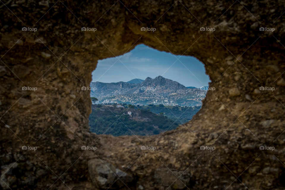 mountain range through a stone window in Ronda, Spain