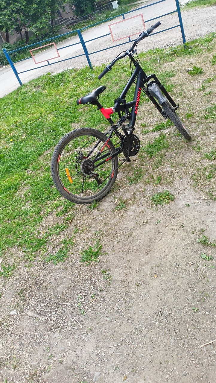 bicycle on the playground, deserted, yard, lawn yellow, red, green, summer, warm sunny day, fence