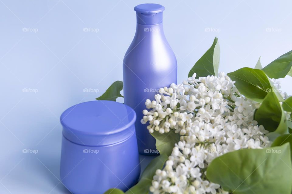 Spring, white fragrant lilac with green leaves.  and jars with cosmetic cream and product.