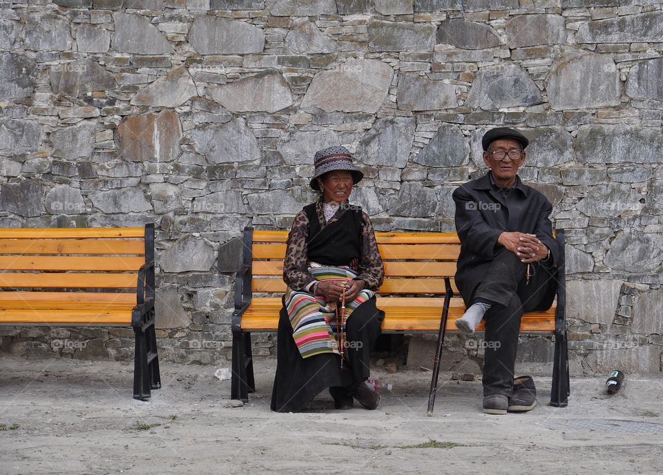 old couple sitting on the bench in buddhist monastery in shigatse