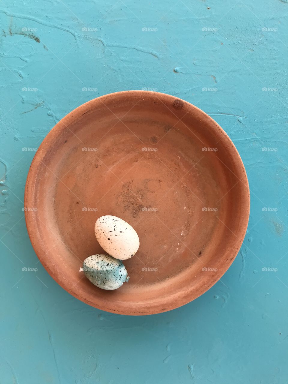 A couple of Robin eggs in a ceramic dish on a light blue background!