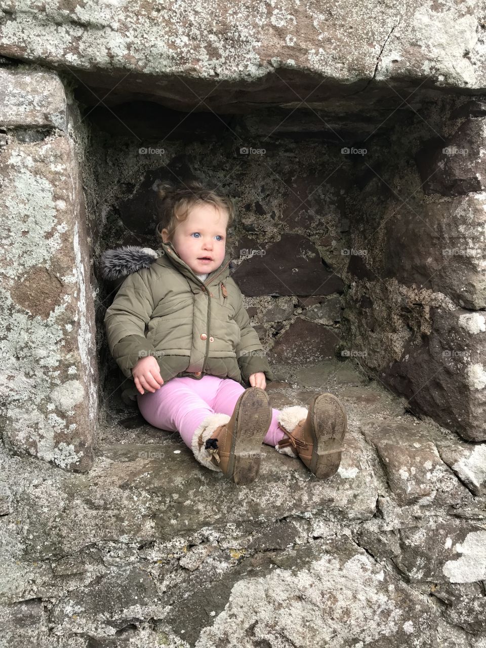 Toddler sitting in a hole in the wall at dunnottar castle
