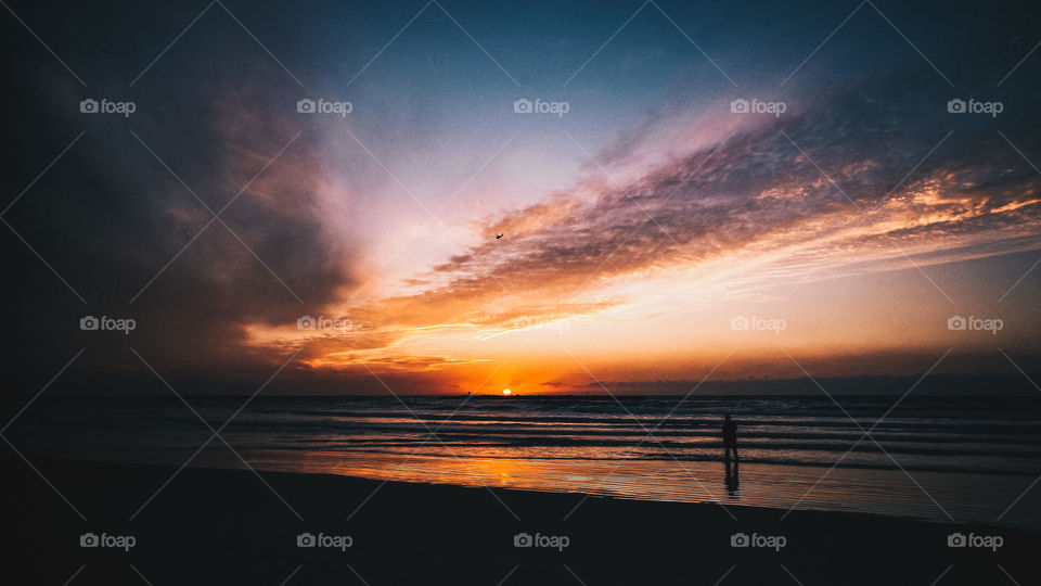 sunset on the shores of the mora, one person walks by the water