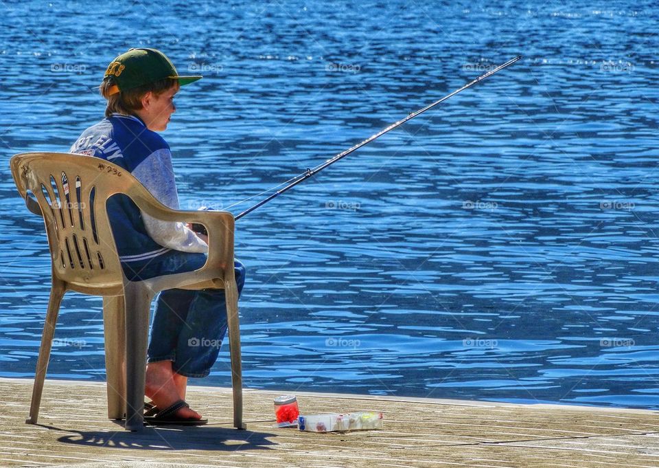 Little Boy Fishing In A Lake. Patiently Waiting For Fish To Bite
