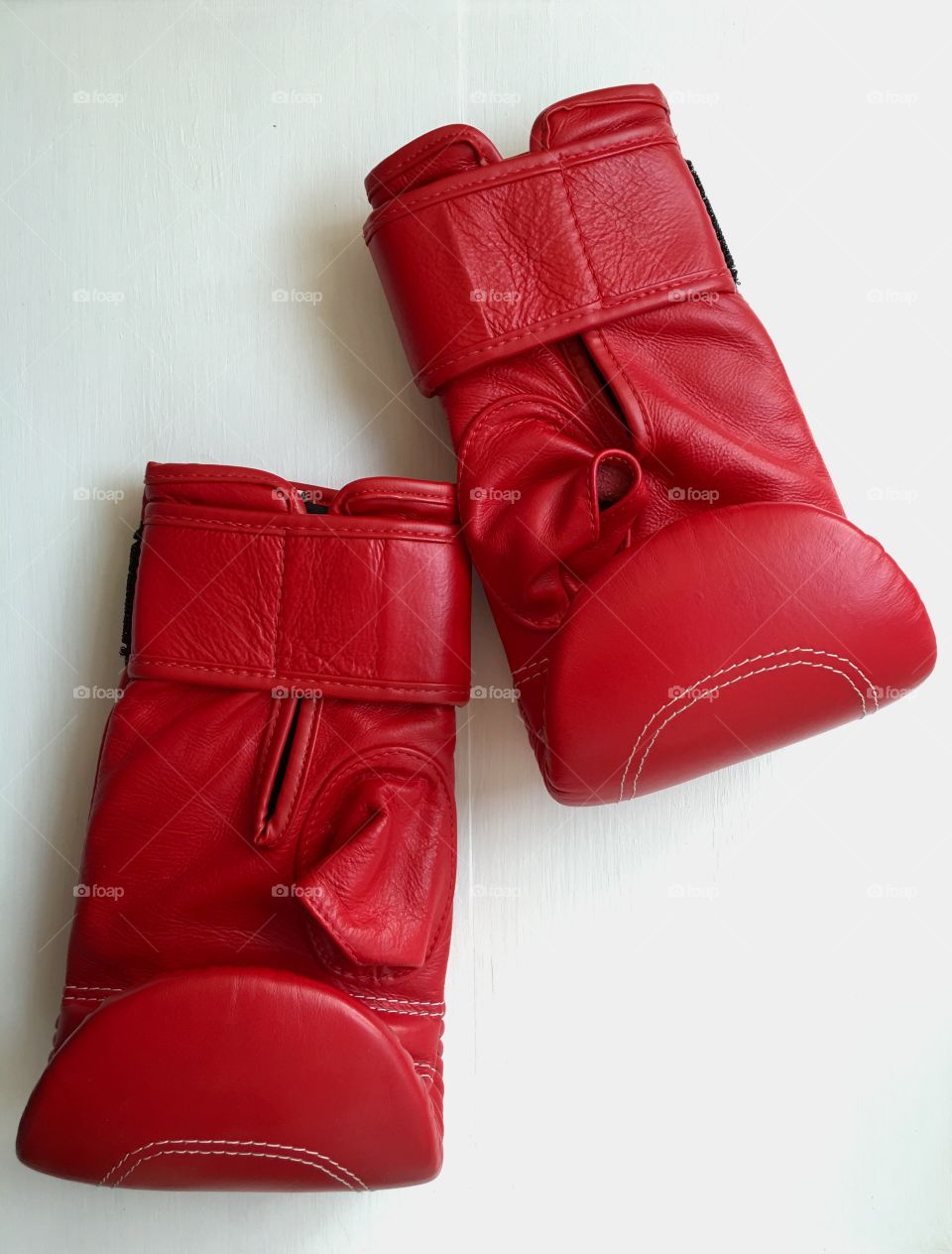 sports equipment, a pair of red leather gloves on a white wooden background, top view