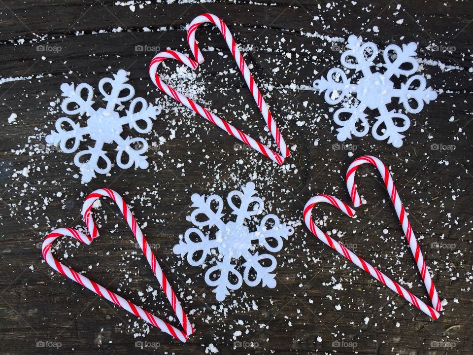 Three hearts made of candy canes on rustic wooden table powdered with snow