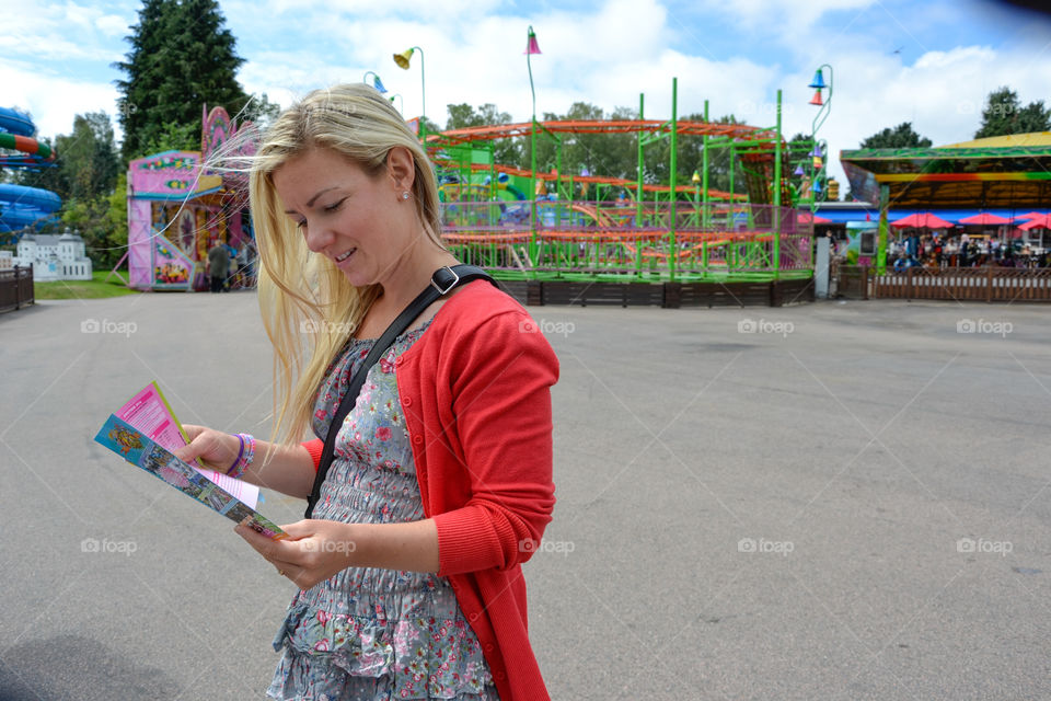 Woman in her 30s visiting Halmstad Adventure park in the summer. Reading the theme park map.