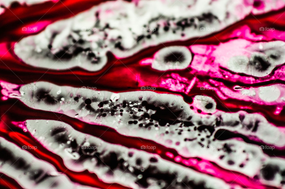 Black and pink refill ink spilled onto the white sink and the ink mixed into abstract blobs and patterns.