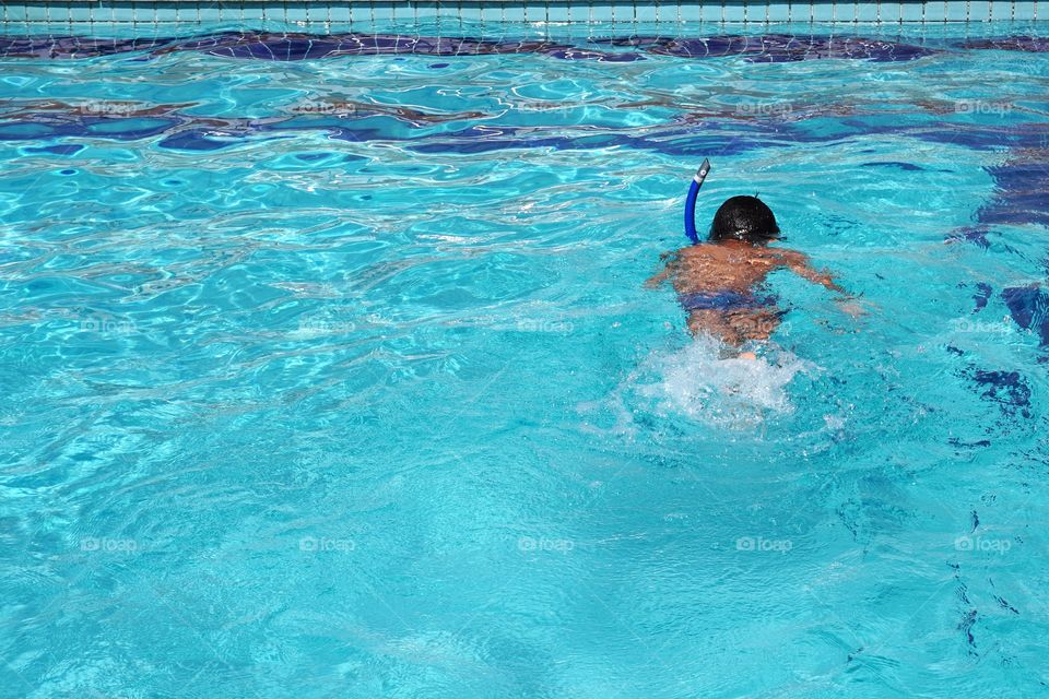 Boy swimming in pool with snorkel 