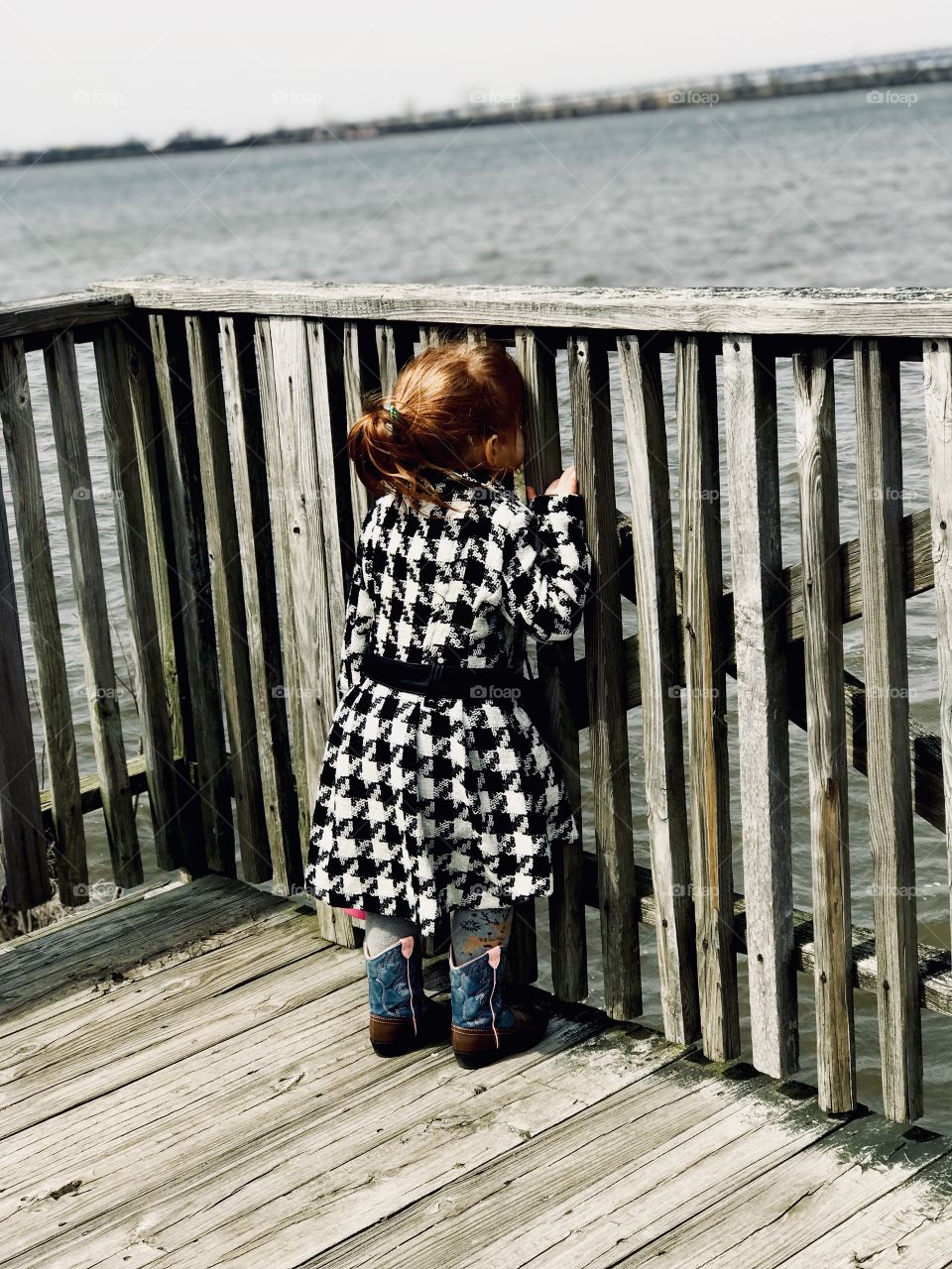 My adorable daughter looking through the bars peering out at the river crashing along the shore. 