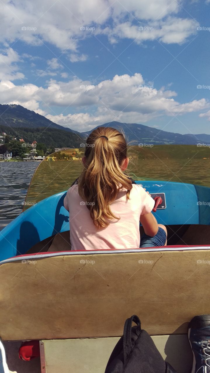 Girl steering boat on mountain lake
