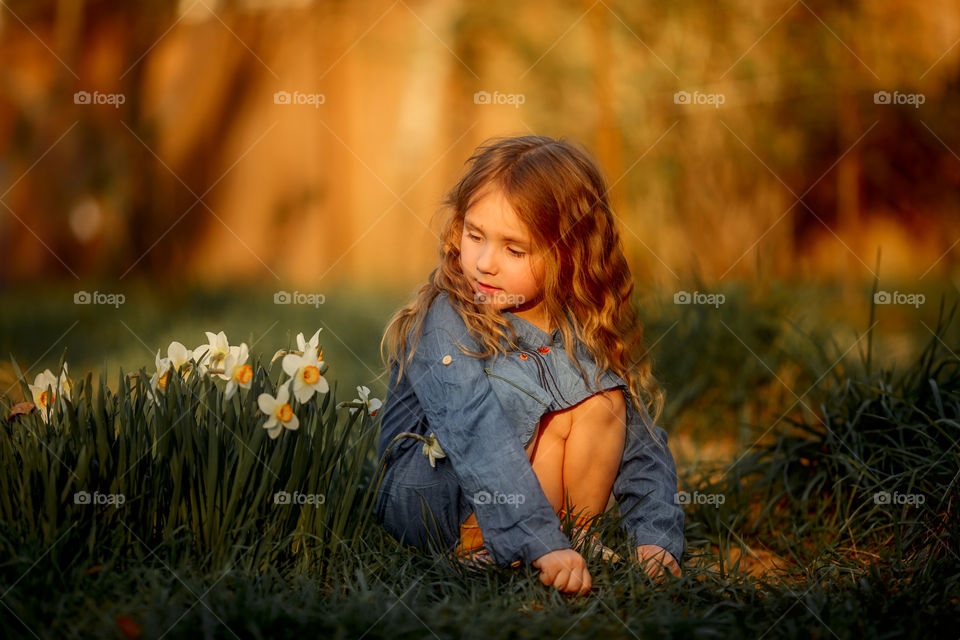 Little girl with narcissus at sunset