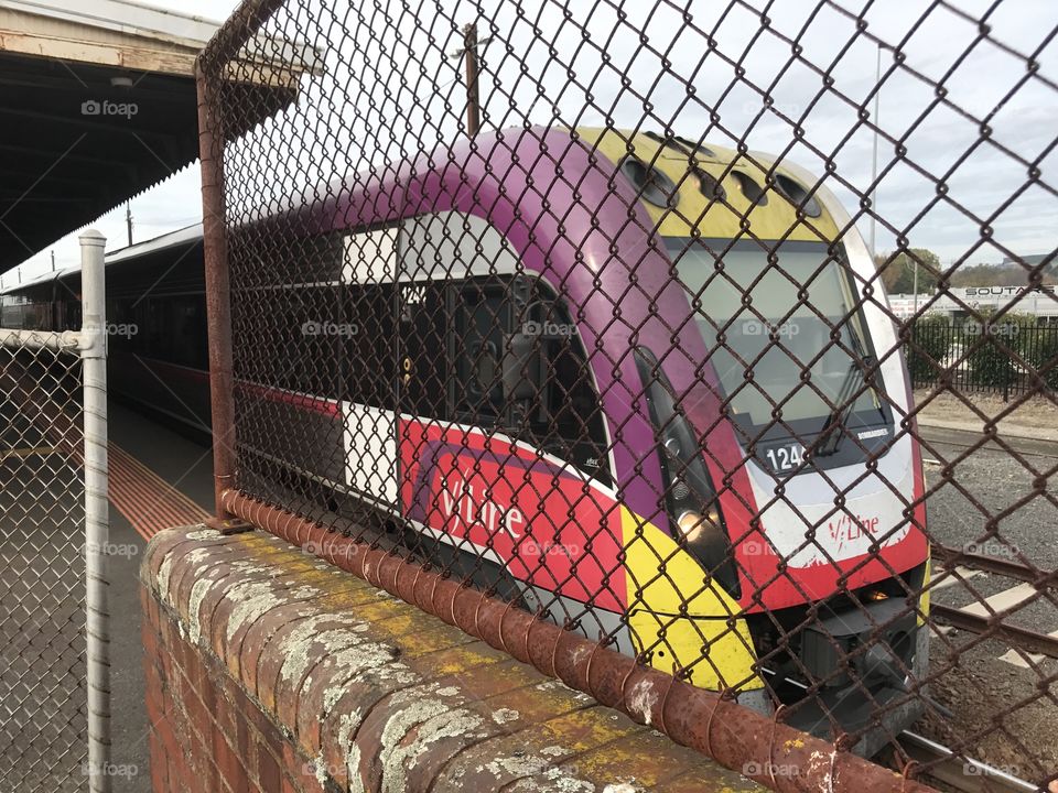 The country train at Warragul Station. Ready to leave taken through a wire fence. Victoria 