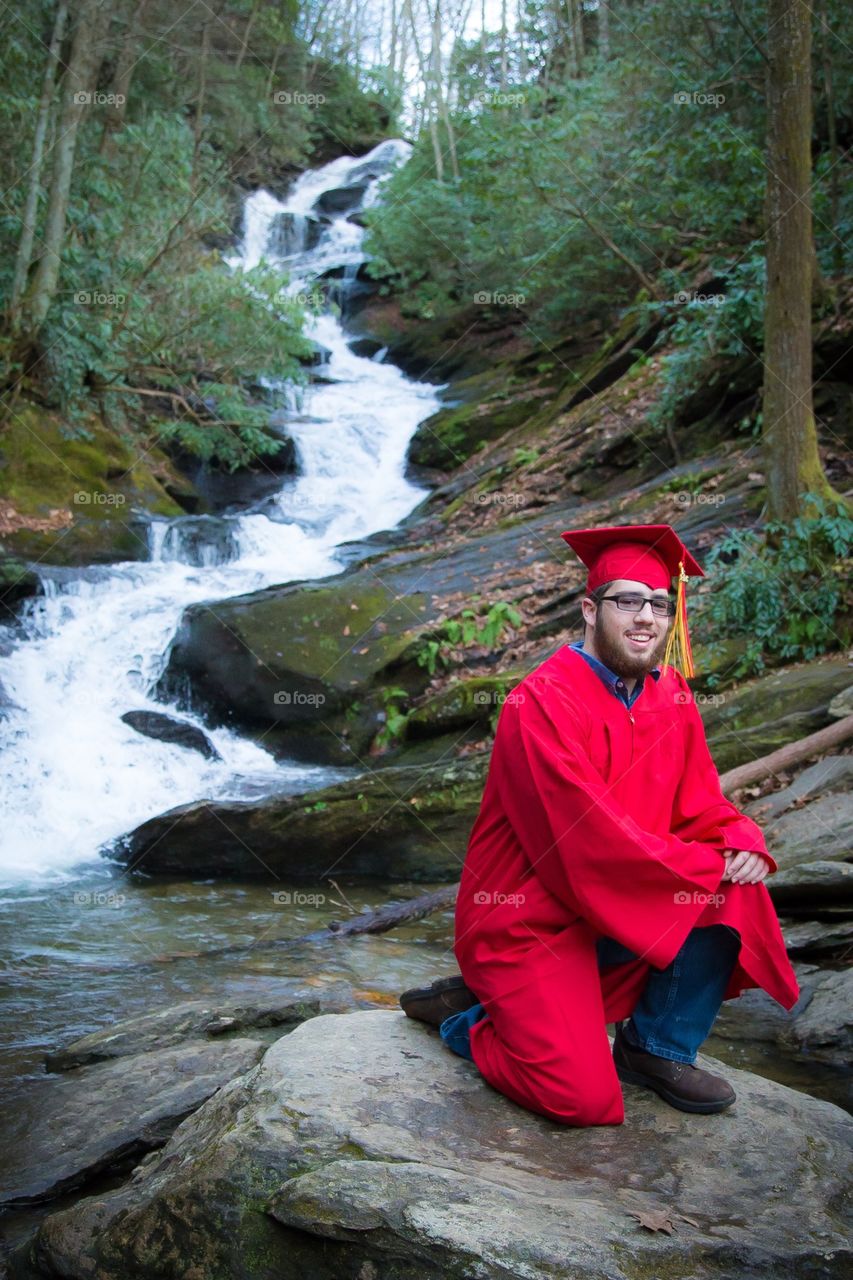 Graduate poses by waterfall Asheville nc 