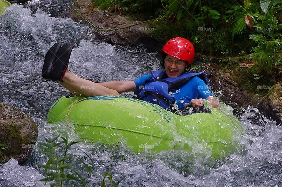 Woman sitting on inflatable tube in river