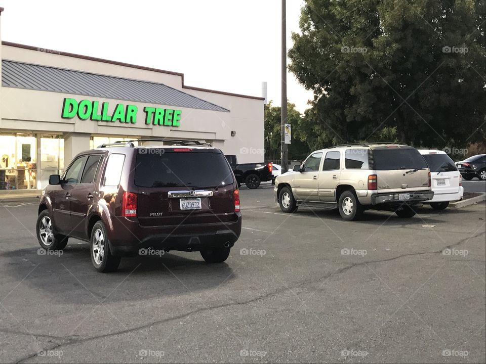 Three vehicles in the parking lot in front of a store.