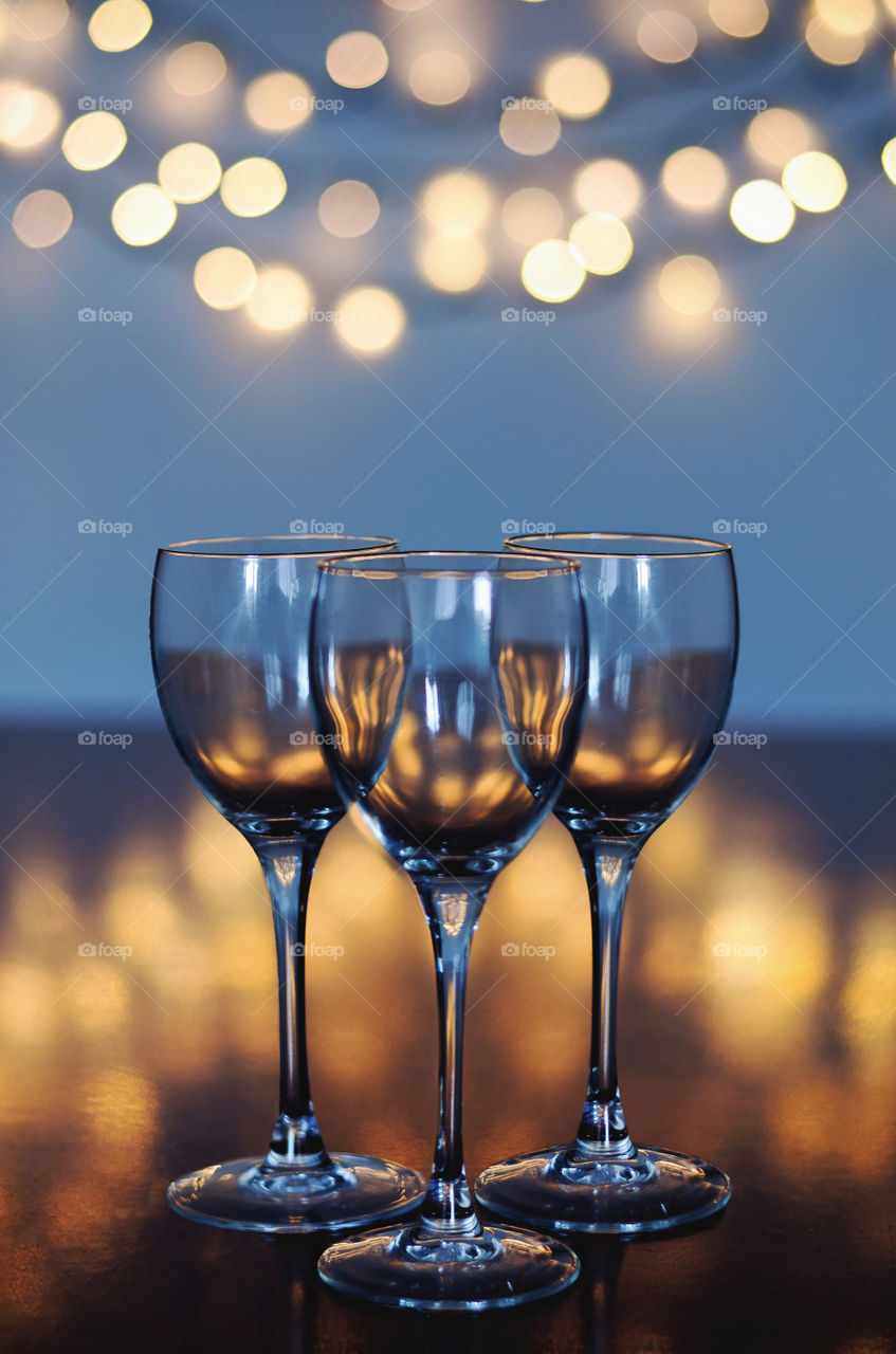 Empty glasses of wine on glass table with bokeh background close up. New year, Christmas mood. Party and holiday celebration concept.