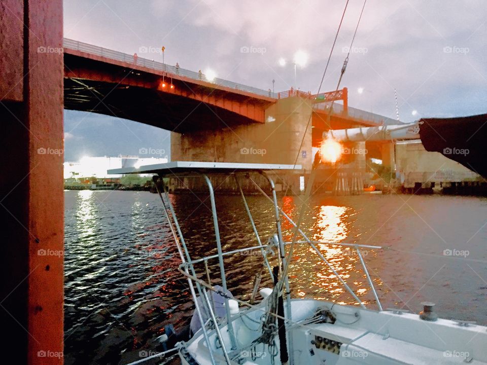 The Pulaski Bridge in Long Island City, Queens, New York at twilight time on a partially overcast day. The sun has just set and casts its last dying rays onto the waters of the East River and the clouds above. Photo from 2018. Hypnotic Productions