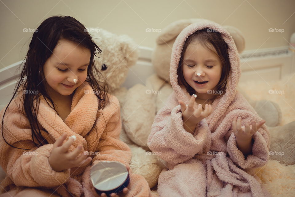 Little sisters in bathrobe with cream